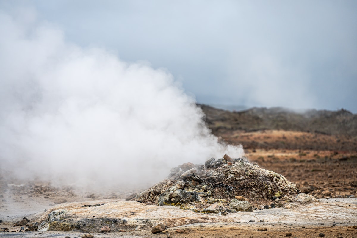 Steam rising from geothermal vents across a barren Icelandic landscape at Hverarond, with blue and violet tones in the low light behind the vapour.
