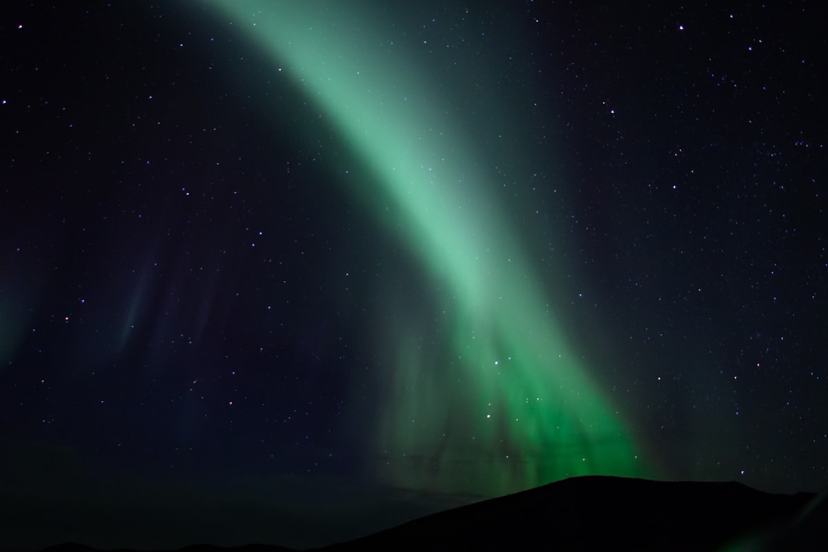Bands of green aurora overhead in Iceland with thin clouds drifting across the lower sky, illustrating the real conditions most aurora hunters work with.