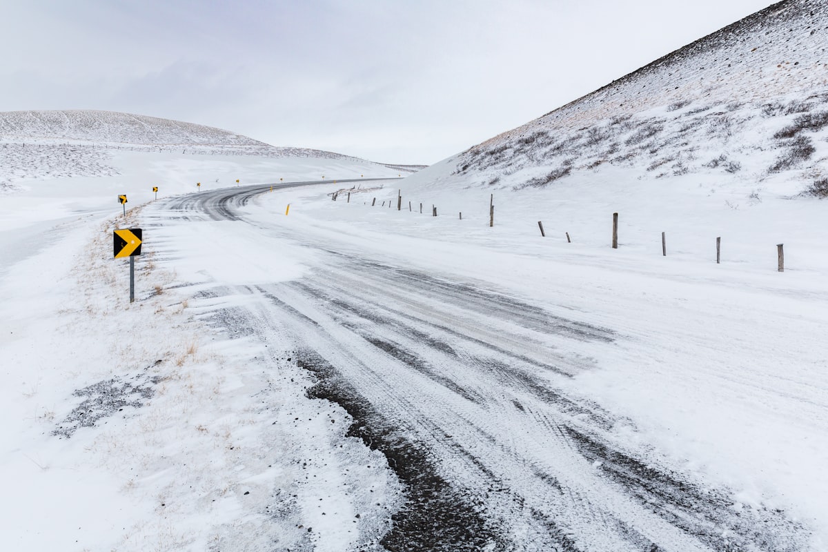 A snow-covered road winding through a barren winter landscape near Lake Myvatn in north Iceland, the kind of unlit rural route an aurora hunter drives after dark.