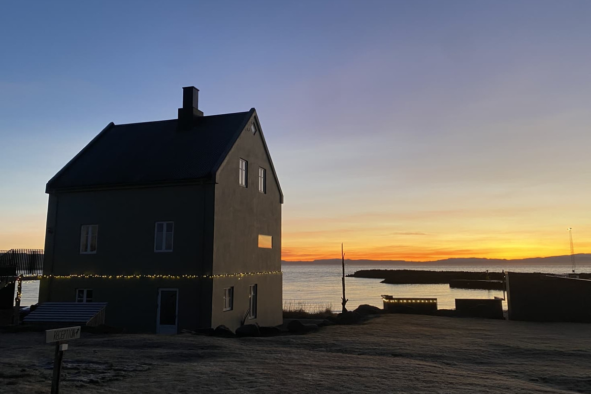 Melar Guesthouse in silhouette against a low sunset over the sea at Kópasker