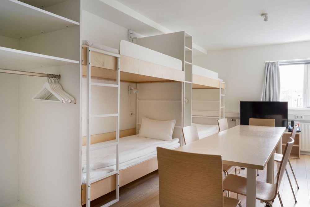 The dormitory at Reykjavik Lights, with pale wooden bunk beds, open hanging space and a shared table